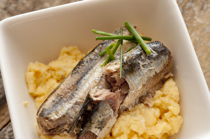 Overhead view of fish breakfast with scrambled eggs in bowl and topped with cut chives