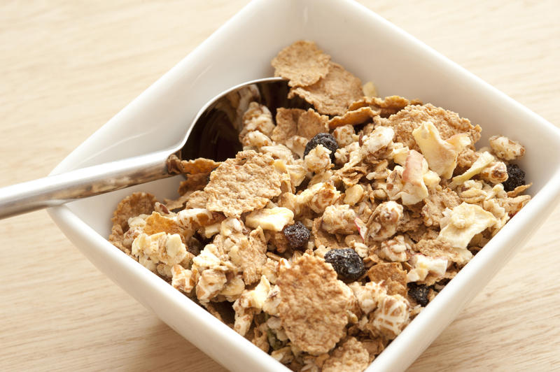 Tasty healthy muesli with dried fruit, raisins and nuts in a square dish with spoon, high angle close up view