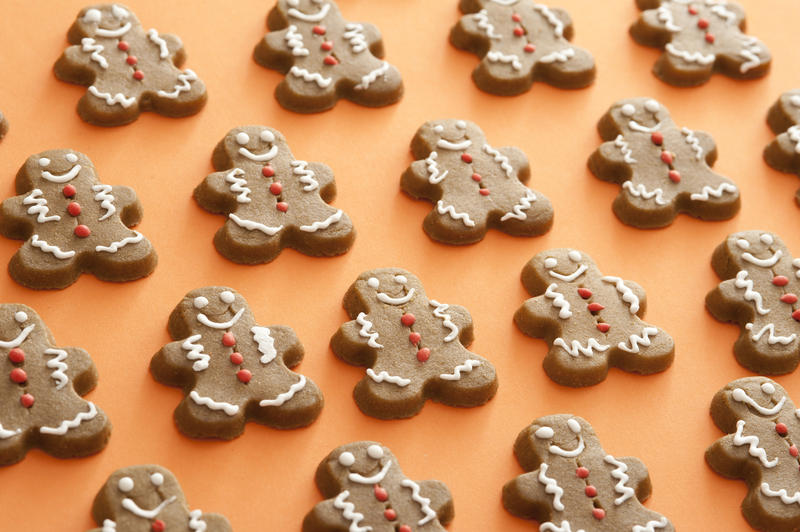 Festive background pattern of gingerbread men laid out on an orange background in neat rows