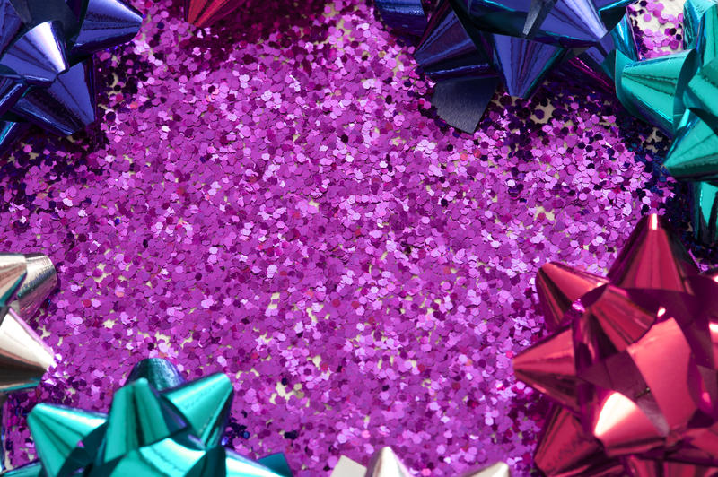a festive background with space for text on pink glitter with brapping bows around