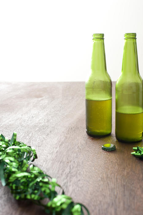 Frame of green ribbons and bottles of beer on wooden table and white background with copy space for saint patricks day concept