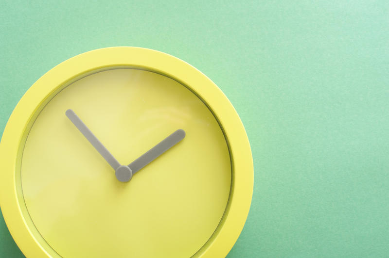 Modern round minimalist green clock with hour and minute hands on a green background with copy space