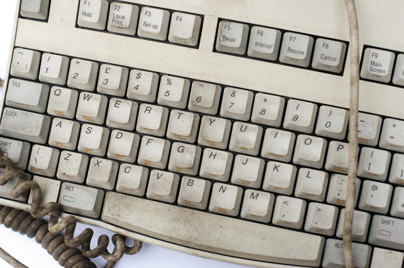 Old dirty grungy white computer keyboard with cords and cables viewed close up from above