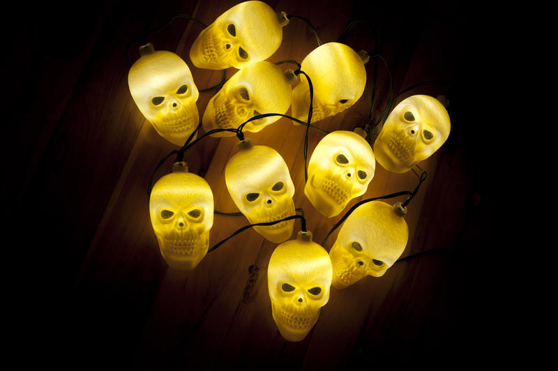 Cluster of ghostly glowing yellow skull lights centered on a dark background to celebrate Halloween