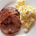 12267   Fried ham slices beside scrambled eggs in plate