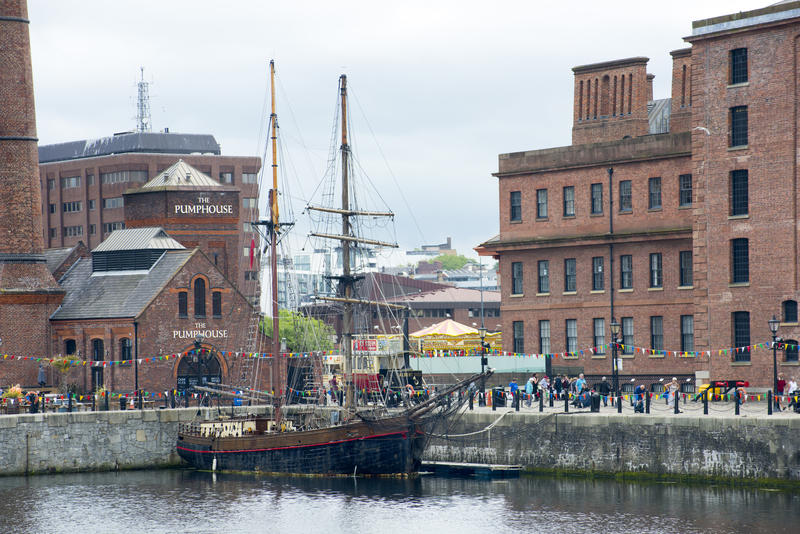 Sailboat or tall ship moored at the quay on the Liverpool waterfront with tourists and historical buildings behind