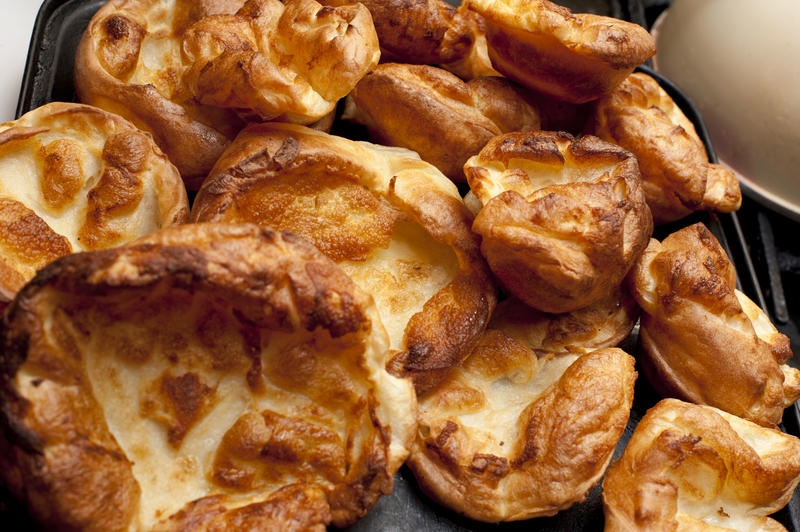 Background of individual small freshly baked homemade Yorkshire puddings ready for serving with a roast meat dish