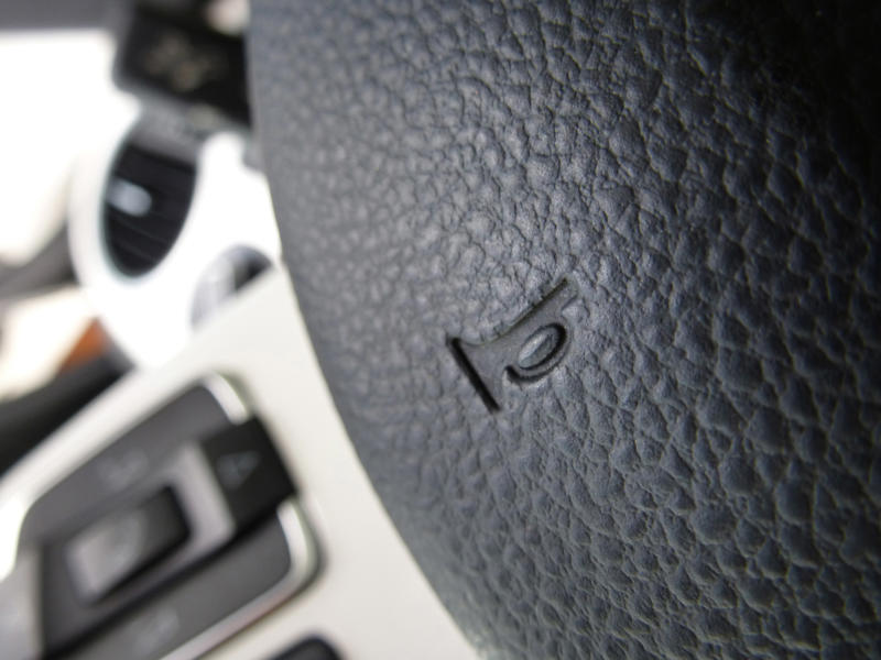 Close up horn symbol on black leather wheel.