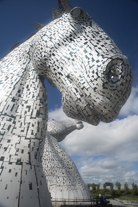 Close up view of one of the Kelpies horse heads at Falkirk, Scotland looking up at the nose from below against a blue sky