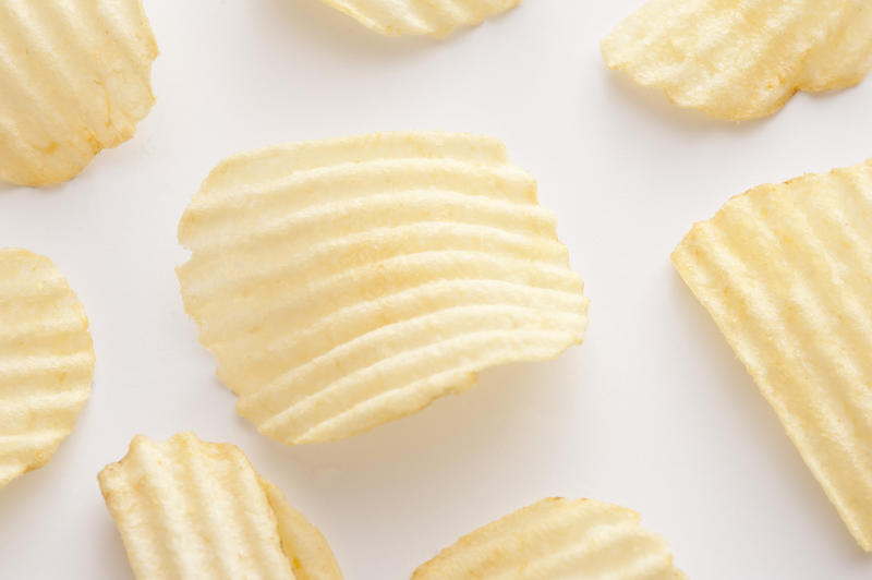 Close up on centered curved ridged potato chip for background about snack or junk food