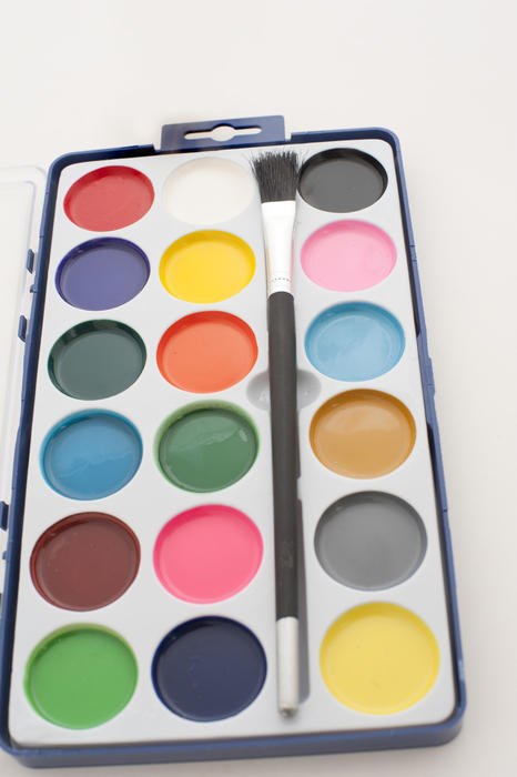 Artists palette of new water color paints in an open brand new box with a paintbrush viewed high angle lengthwise