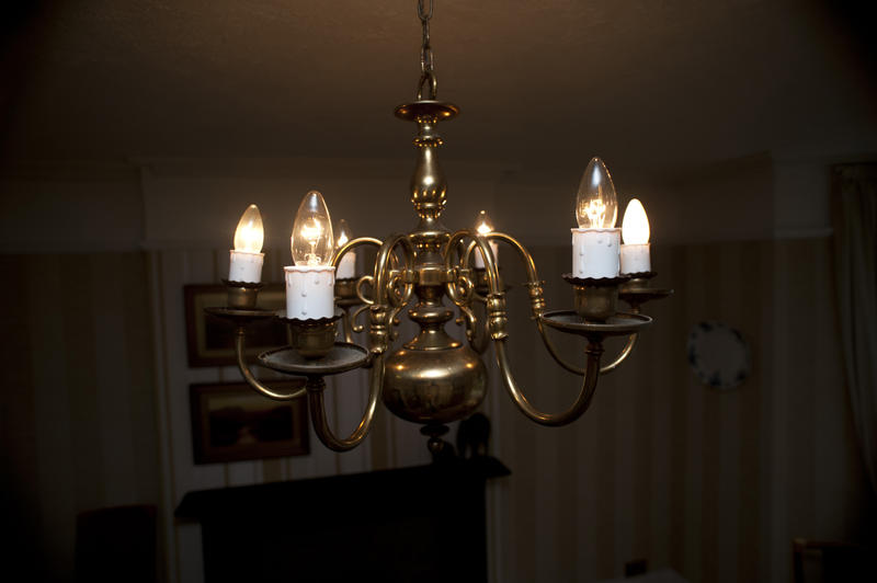 Close Up of Brass Chandelier with Candle Shaped Lightbulbs Hanging from Ceiling in Room of Home