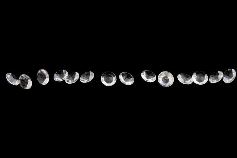 Row of faceted cubic zirconia or glass forming a sparkling of gemstones row resembling diamonds over a black background with copy space