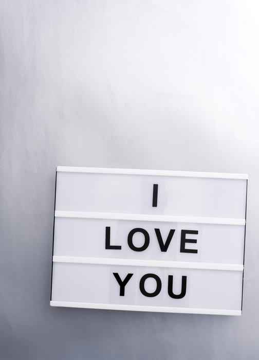 I Love You sign with black changeable letters on white lightbox against silver wall background with copy space