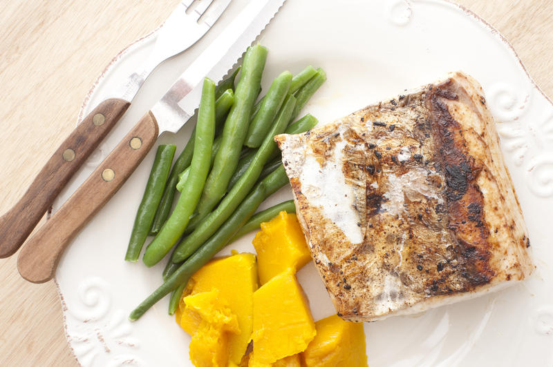 First person perspective view on nutritious and delicious serving of baked mackerel with squash and beans beside fork and knife