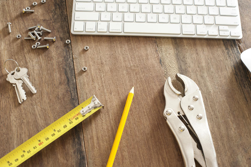 a design engineers desk with pencil, tape measure and adjustable wrench