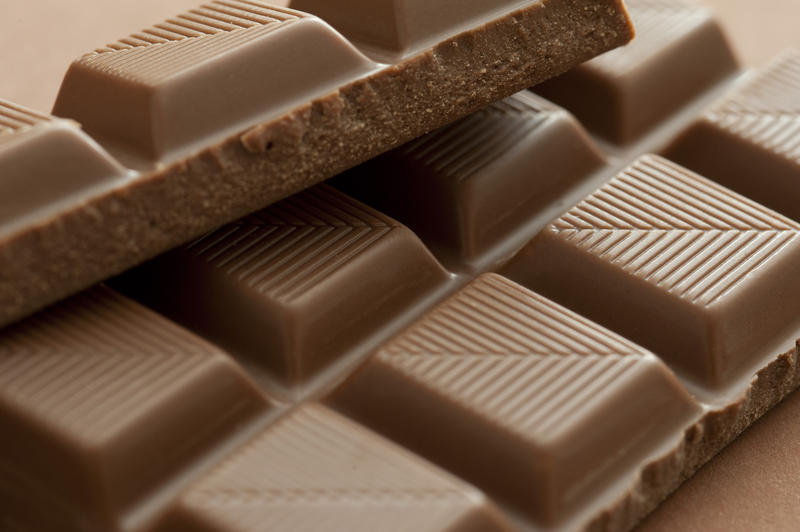 Close up on squares of delicious milk chocolate with broken texture and lines for snacking or cooking