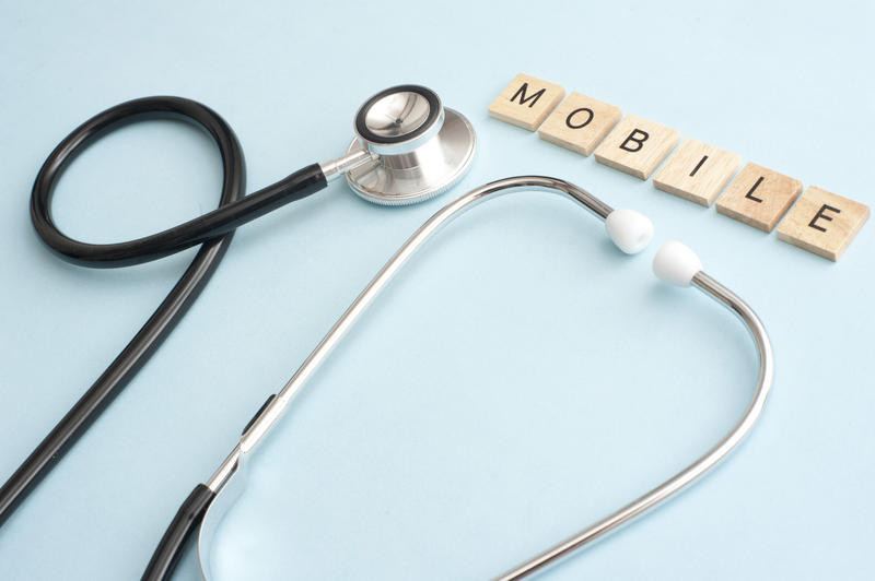 Mobile website analytics concept display of medical stethoscope and small letters on wooden blocks over blue background