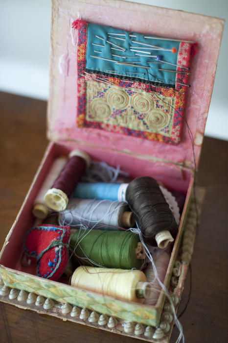 Open sewing box with reels of colorful thread and needles and pins in a cushion in the lid in a high angle view