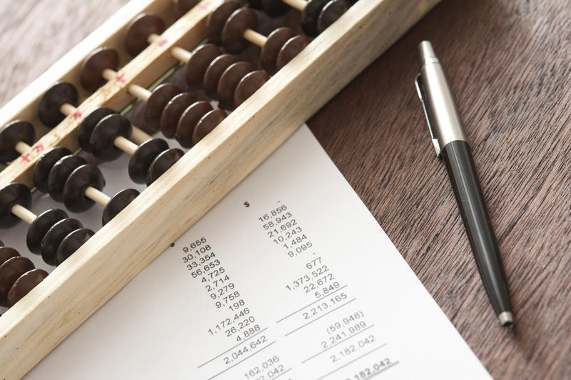 Abacus with balance sheets and pen lying on a wooden desk in a business and accounting concept viewed from above