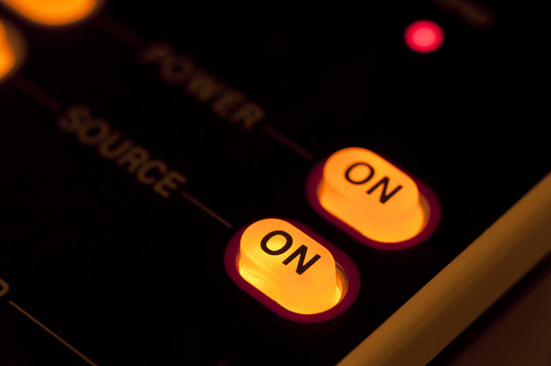 Illuminated orange on off power buttons glowing on a dark panel in a close up view