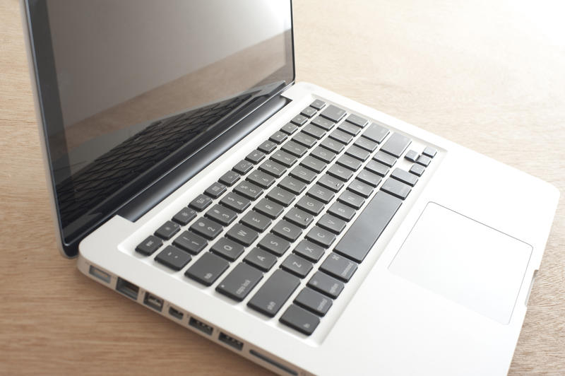 Open laptop computer viewed from the side with light flare in the background on a wooden desk