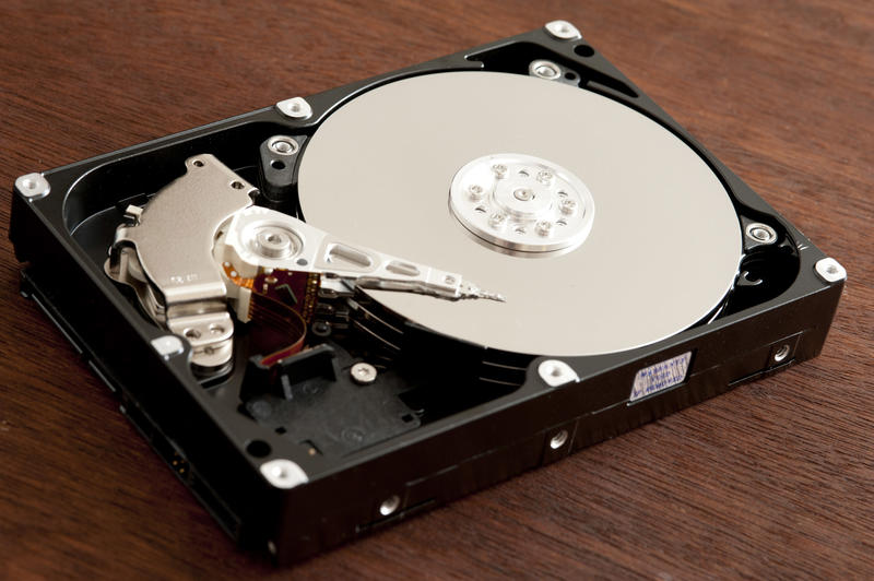 Open hard disk drive HDD close-up over dark wooden background