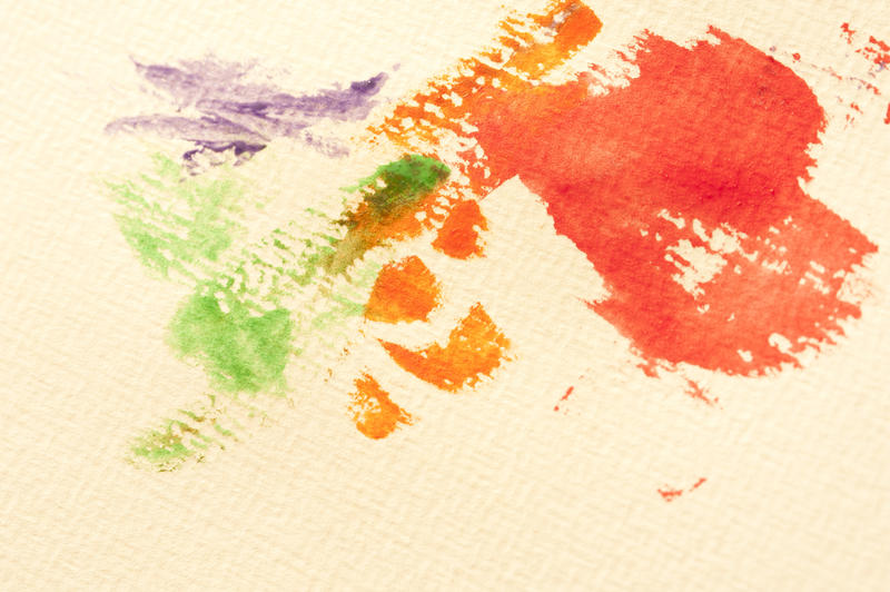Random green, purple, orange and red paint splotches on yellow canvas paper