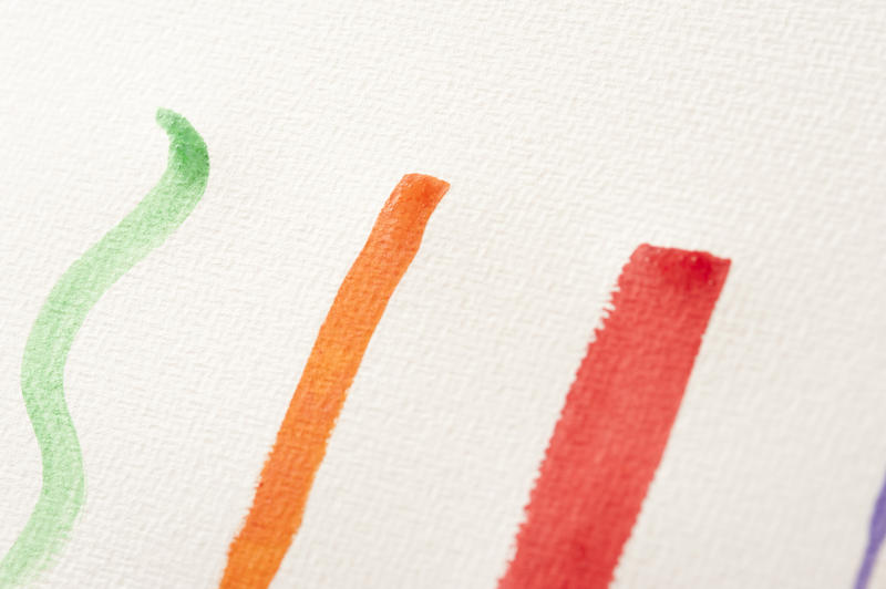 Three various width paint strokes in green, orange and red lines on white paper with canvas texture