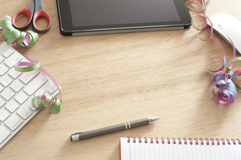 Pleasing background with copy space surrounded by keyboard, pen, notebook, tablet computer, ribbon and scissors