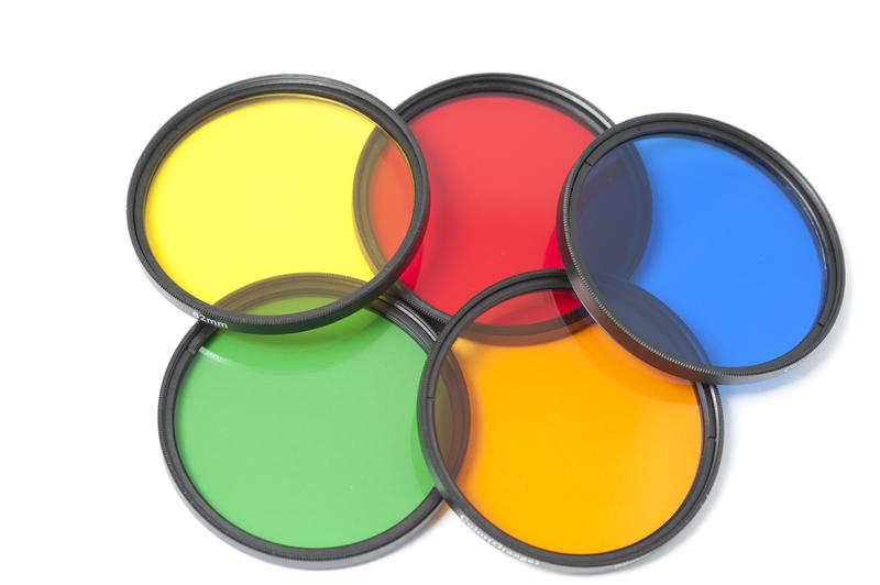 Set of five yellow, red, blue, green and orange camera photo contrast filters neatly arranged on isolated white back round