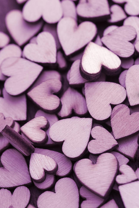 Pile of small purple craft wooden hearts cut from plywood, full frame background concept