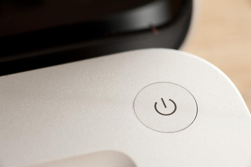 Close up view of a power button on a laptop computer with the lid open on a curved corner