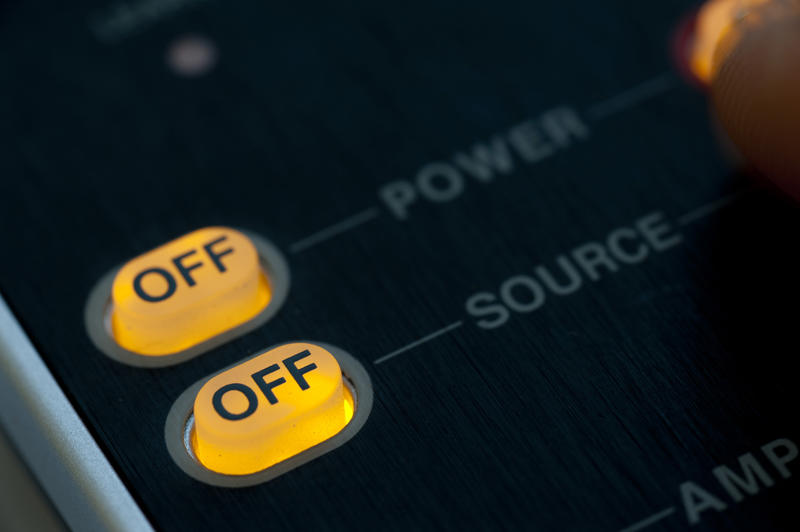 Illuminated glowing On Off power buttons on a dark electronic control panel with text - power - and - source