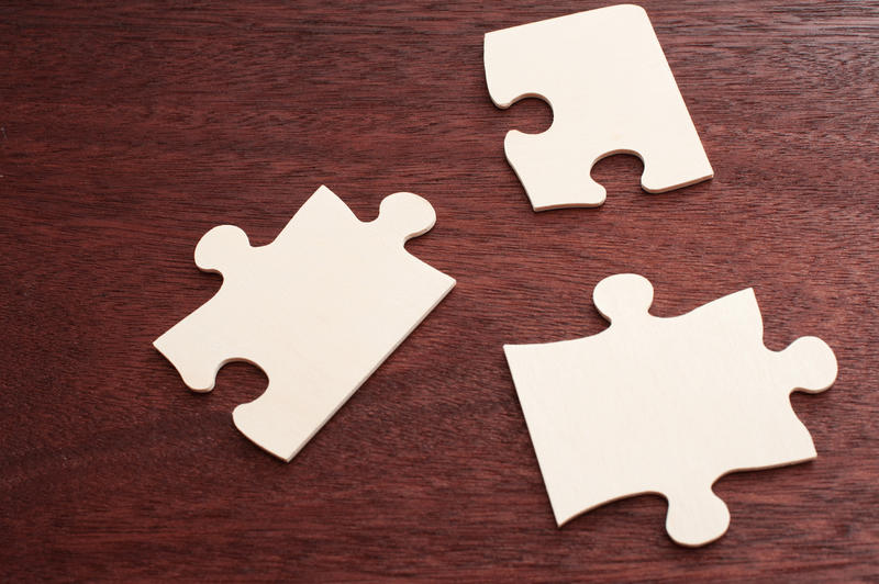 Top down view on three incomplete blank puzzle pieces with copy space over brown table
