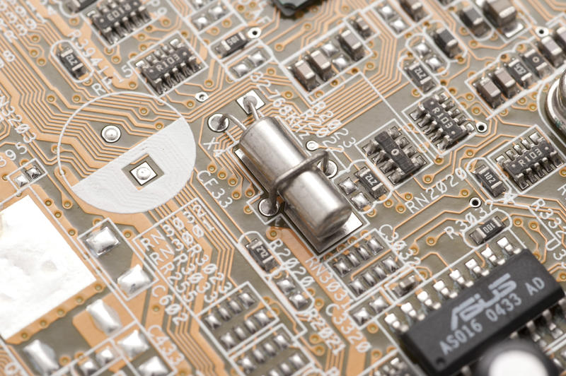 Cilindric quartz crystal can oscillator on electronic layout of motherboard