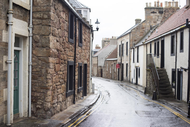 Narrow curved street and sidewalks surrounded by quaint old houses in Cellardyke, Scotland