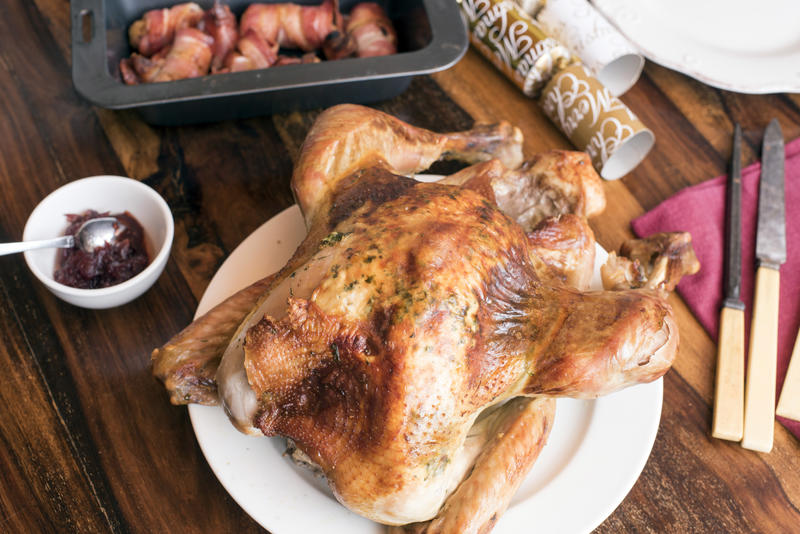 Roast Christmas turkey with accompaniments on a festive holiday table with crackers and carving utensils