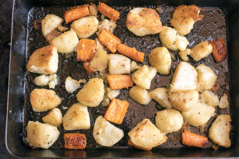 Mixed healthy fresh roast vegetables on a metal baking tray straight from the oven viewed full frame from overhead