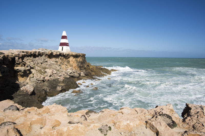 Rough seas on the coast of Robe Australia with the Robe Obelisk on a rocky headland with eroded cliffs viewed from a clifftop vantage point or lookout