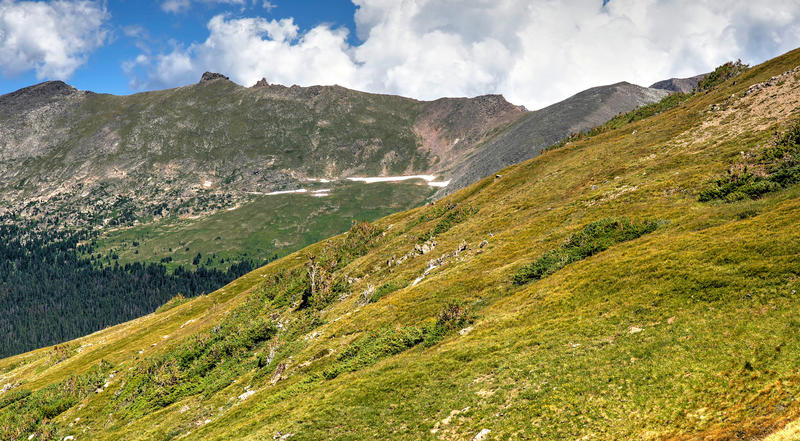 <p>High altitude tundra sweeps upward towards a jagged mountainous skyline at Rocky Mountain National Park. &nbsp; &nbsp;Meanwhile, afternoon thunderclouds gather together above lofty peaks.</p>
