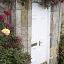 12963   Roses growing around stone block cottage door