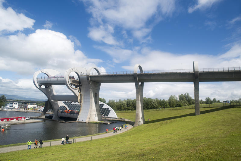 People walking past the Falkirk Wheel in Falkirk, Scotland, a rotational boat lift connecting two canal transport systems