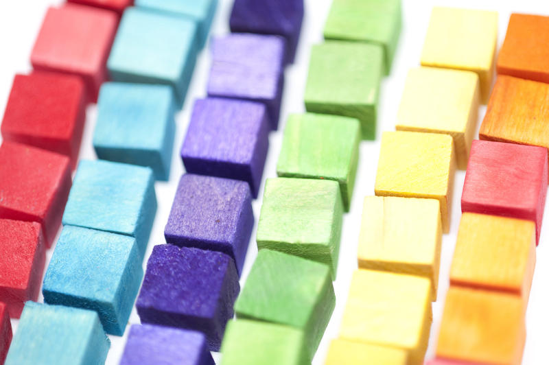 Close up low angle view of rows of neat colorful toy wooden blocks arranged by color in a full frame background