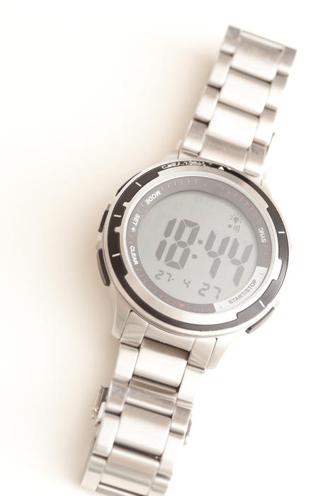 Overhead view of a digital mans wrist watch with shiny silver metal bracelet strap and case over a white background with copyspace