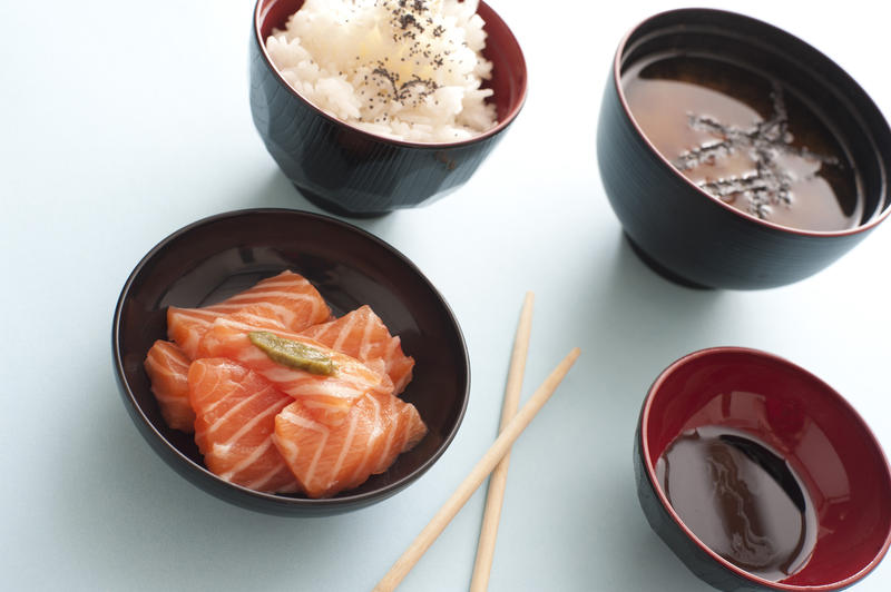 Gourmet fresh raw salmon sashimi served with individual bowls of soy sauce and rice for a delicious Japanese meal