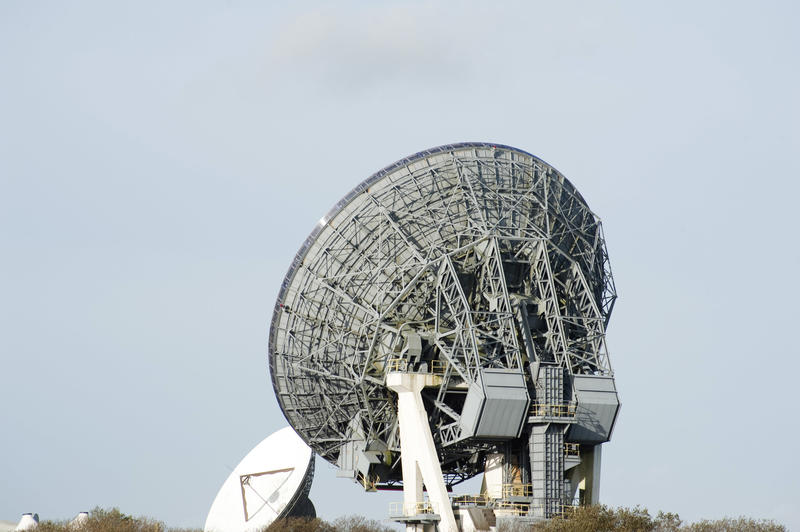 Satellite ground dish antenna from its back low angle view against greyish sky