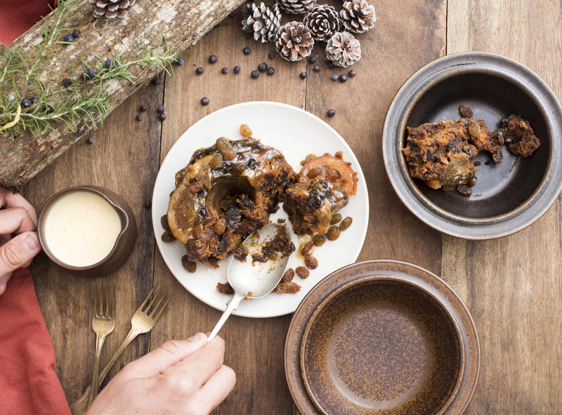 Person spooning up a serving of Christmas dessert to place it in a bowl in an overhead view at the table