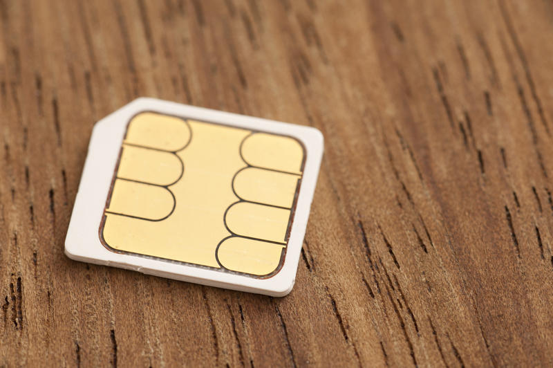 Micro sim card with chip side up close-up on wooden table