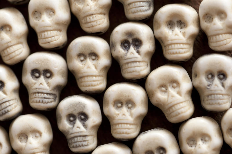 Background of white plastic toy skulls in a neat arrangement viewed from above for Halloween or horror themes